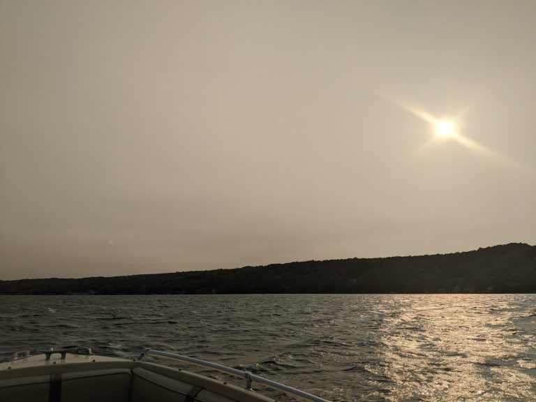 Smoky view of the lake with the sun glimmering in the dark gray sky